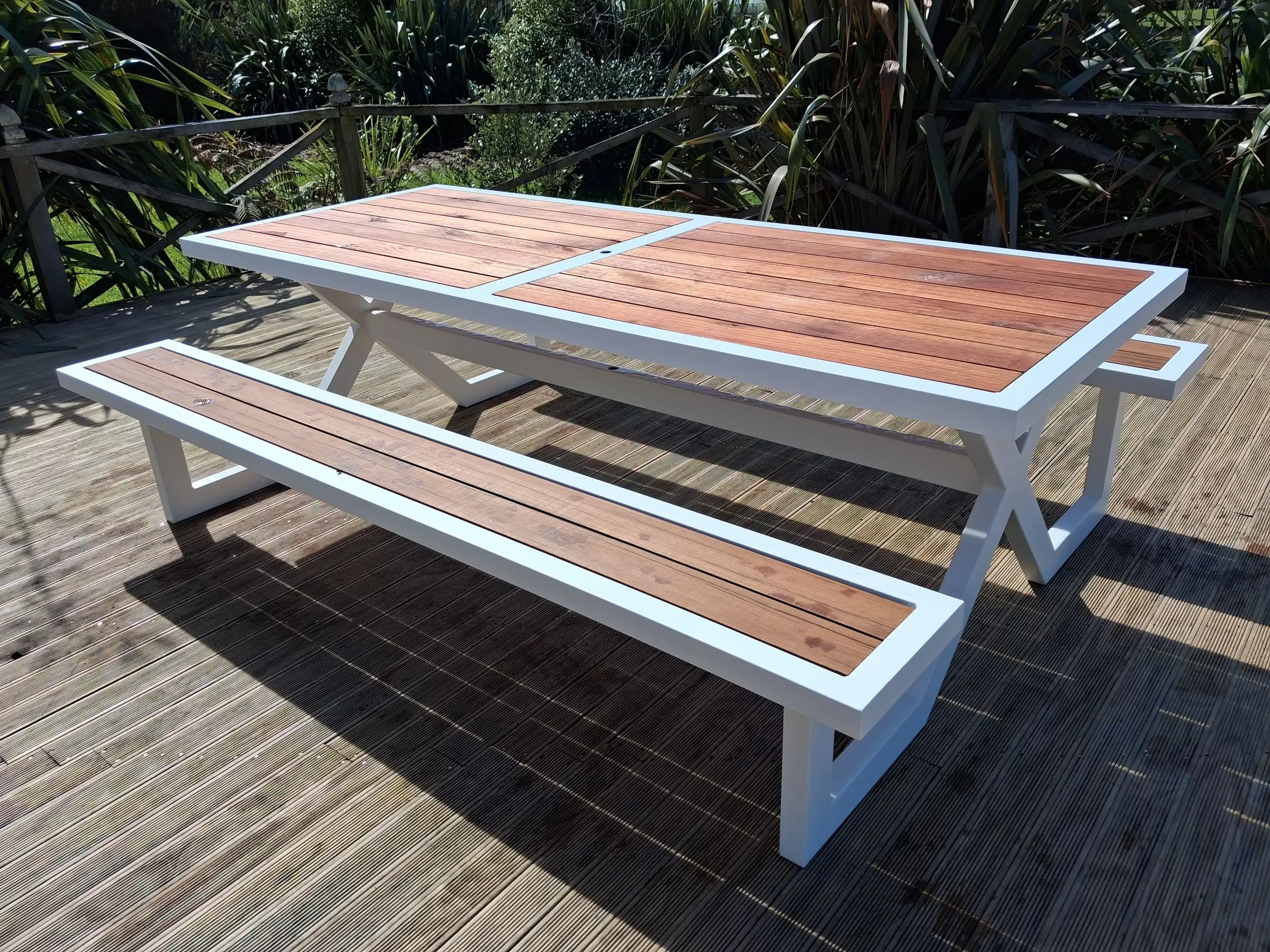 White powder-coated aluminium picnic table with a hardwood slat top and bench seats on a deck