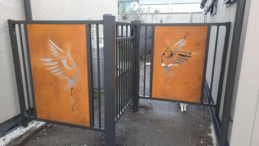 Charcoal aluminium gates with laser-cut Corten bird-in-flight panels