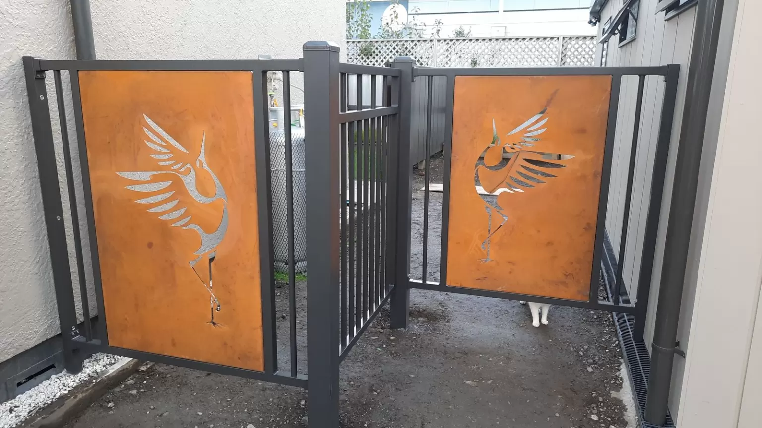 Charcoal aluminium gates with laser-cut Corten bird-in-flight panels