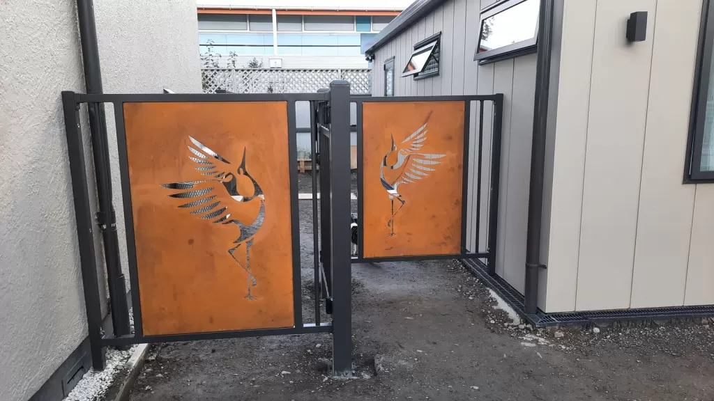 Side view of aluminium gates with Corten decorative panels beside a house