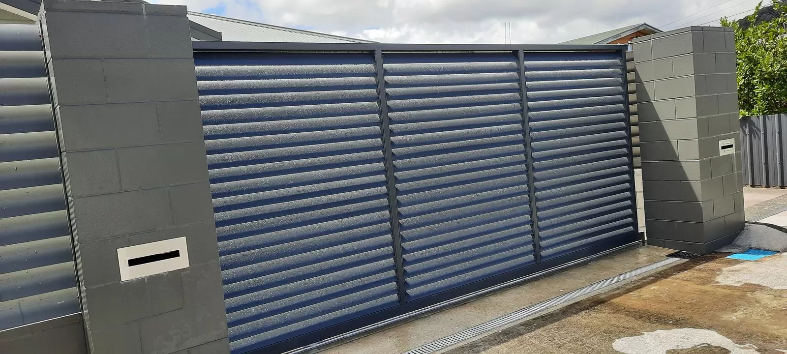 Louvred aluminium sliding gate between block pillars