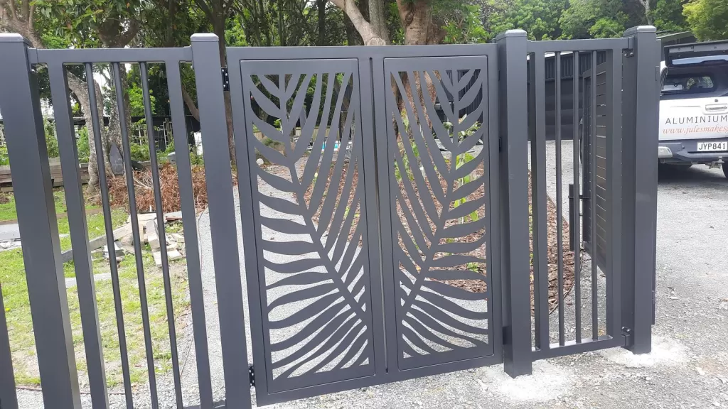 Charcoal aluminium double gates with laser-cut palm frond panels set into matching aluminium fencing