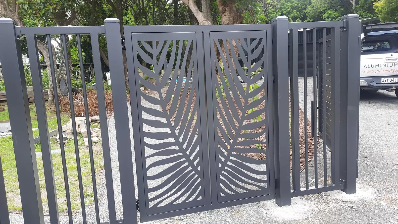 Charcoal aluminium double gates with laser-cut palm frond panels set into matching aluminium fencing