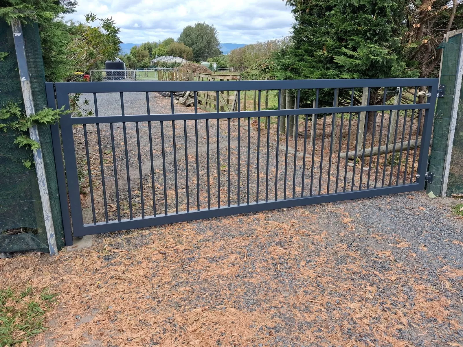 Single aluminium swing gate across a gravel driveway near Hokio Beach, Levin