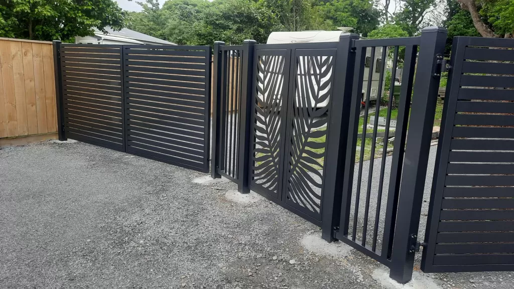 Charcoal aluminium slat fence with palm frond laser-cut double gates and a pedestrian gate