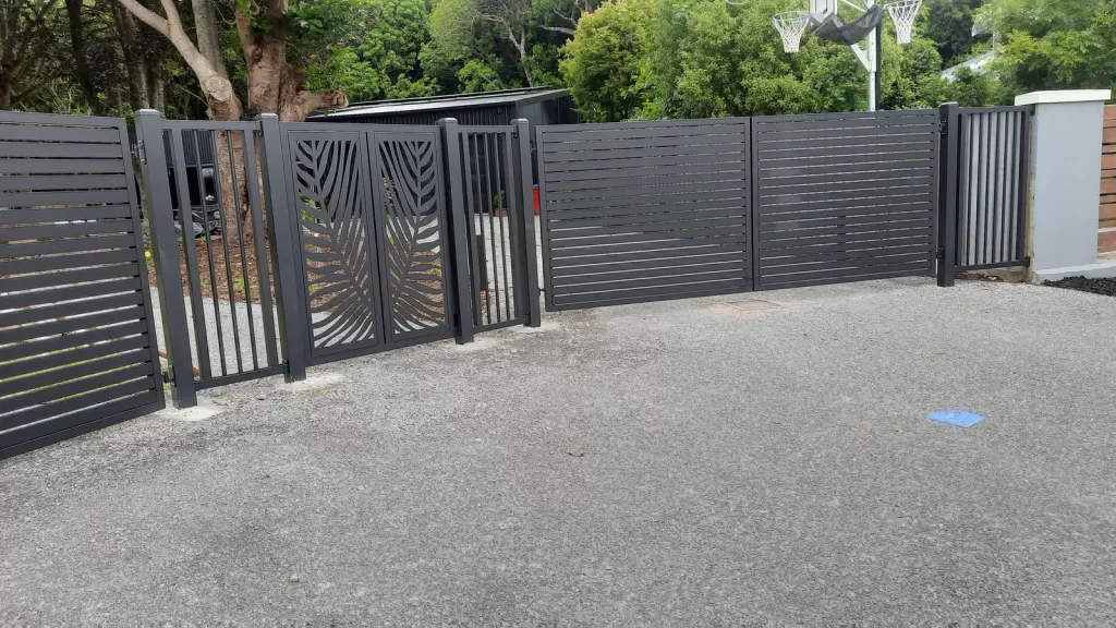 Wide view of aluminium slat fencing and decorative gates across a driveway