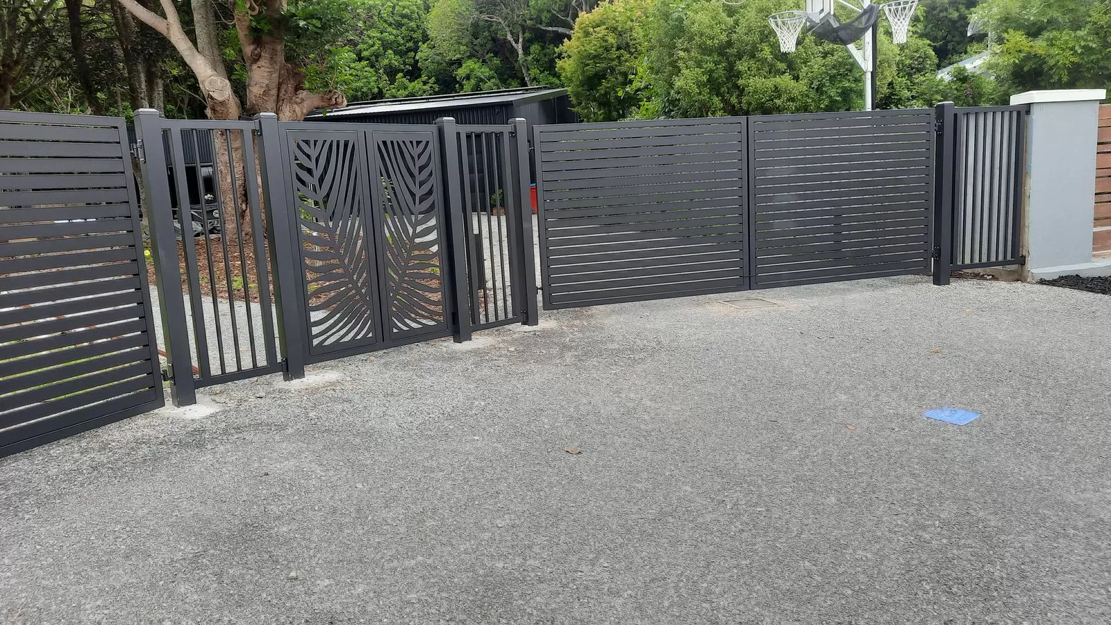 Wide view of aluminium slat fencing and decorative gates across a driveway