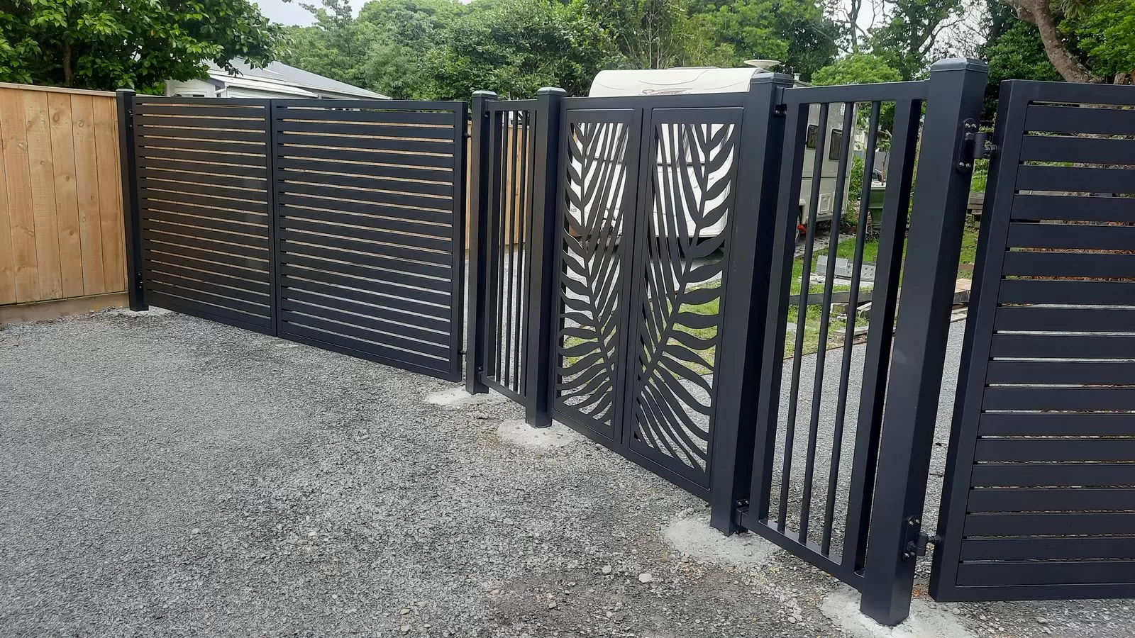 Charcoal aluminium slat fence with palm frond laser-cut double gates and a pedestrian gate