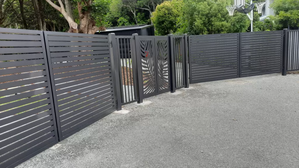Full property frontage with charcoal aluminium slat fencing, driveway gates and a pedestrian gate