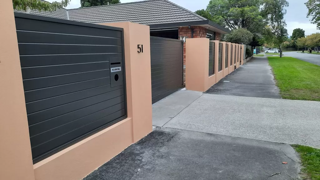 Charcoal aluminium slat infill panels with a built-in letterbox between rendered pillars