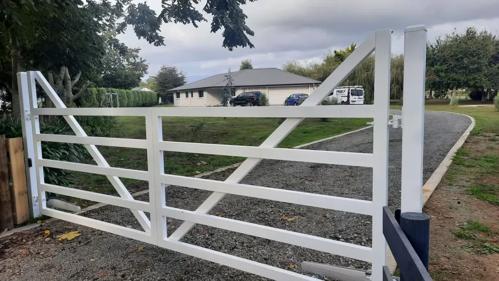 White aluminium farm-style swing gate with diagonal brace on a lifestyle block
