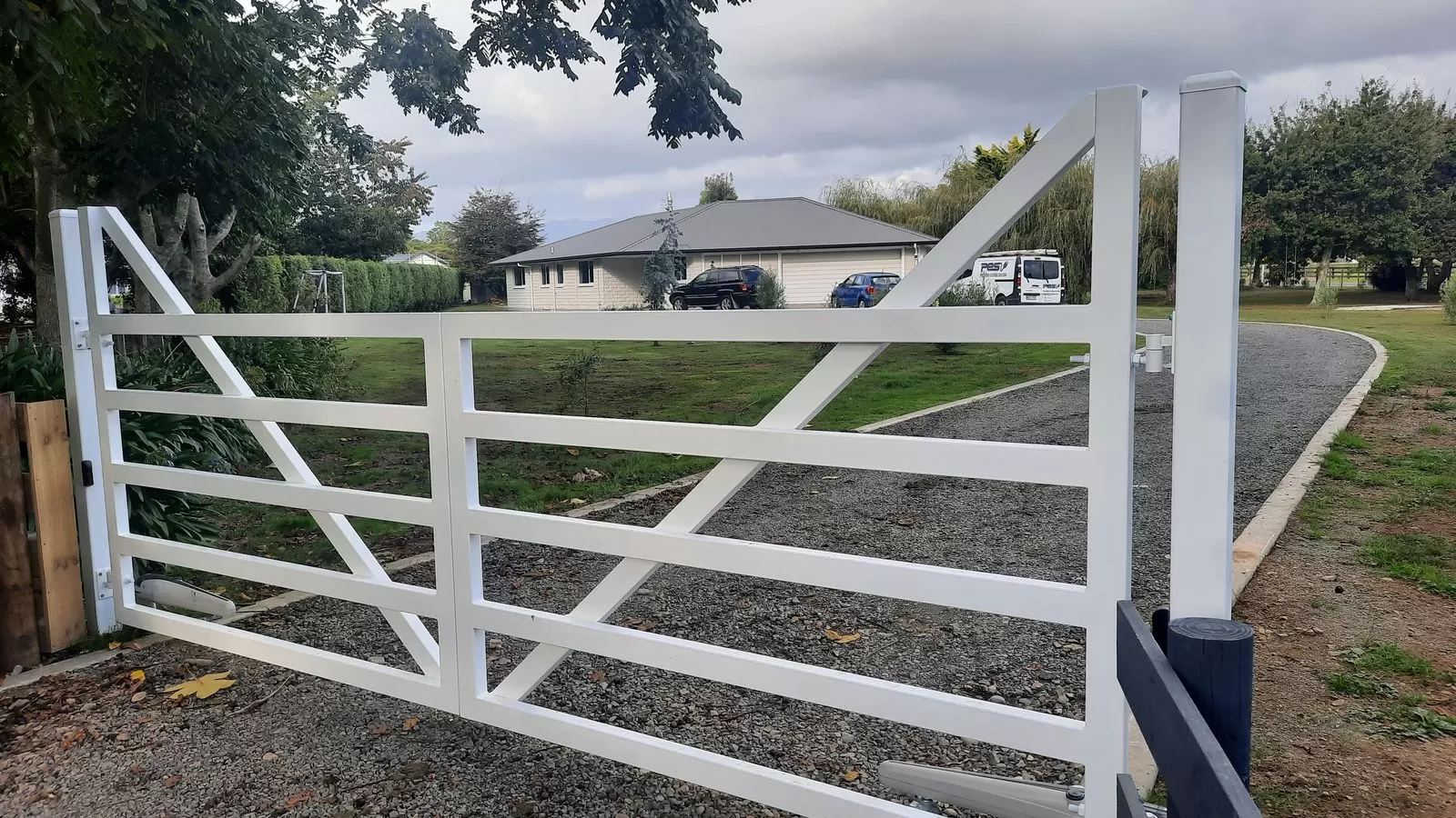 White aluminium farm-style swing gate with diagonal brace on a lifestyle block
