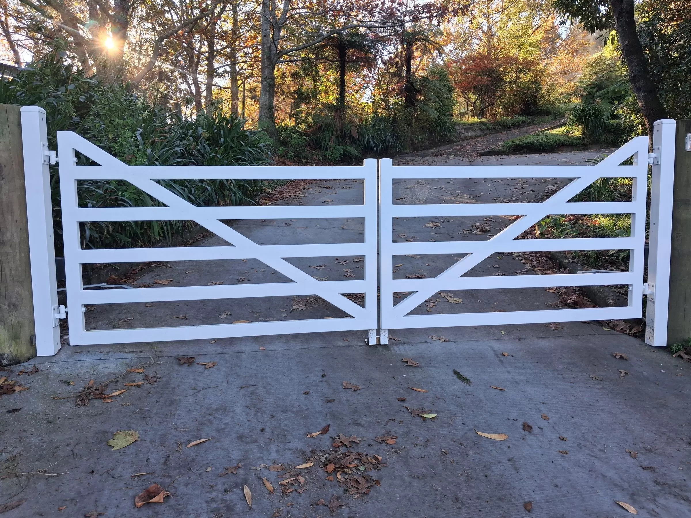 White rural-style aluminium double swing gates on a driveway in Waikanae, Kāpiti Coast